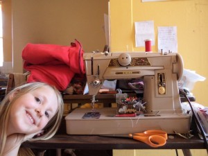 small girl standing to one side of sewing machine