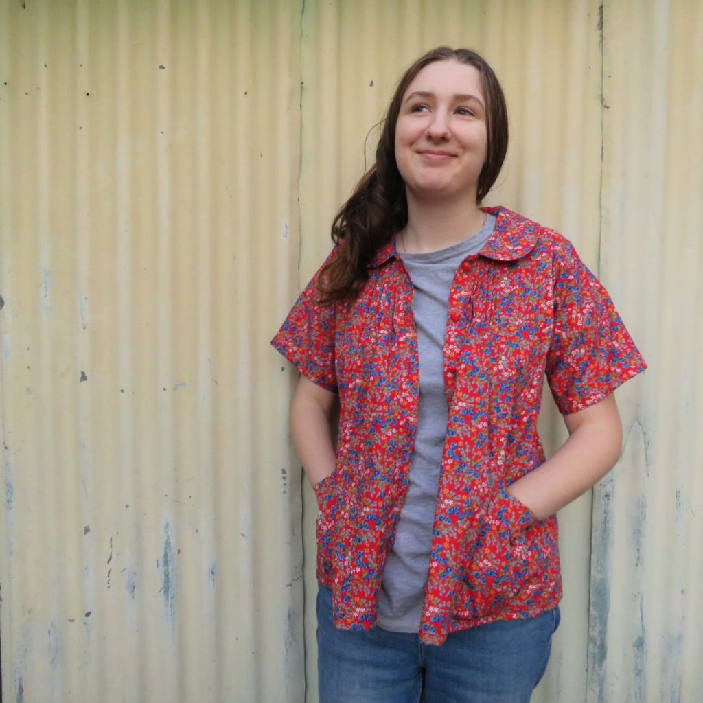 Red Petrea blouse worn unbuttoned with grey t-shirt and jeans.