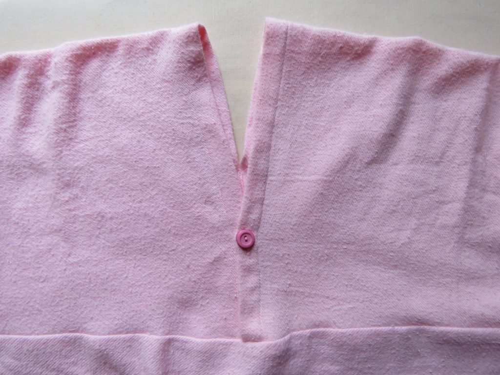 Neckline detail of pink flannelette nightie, showing button. 